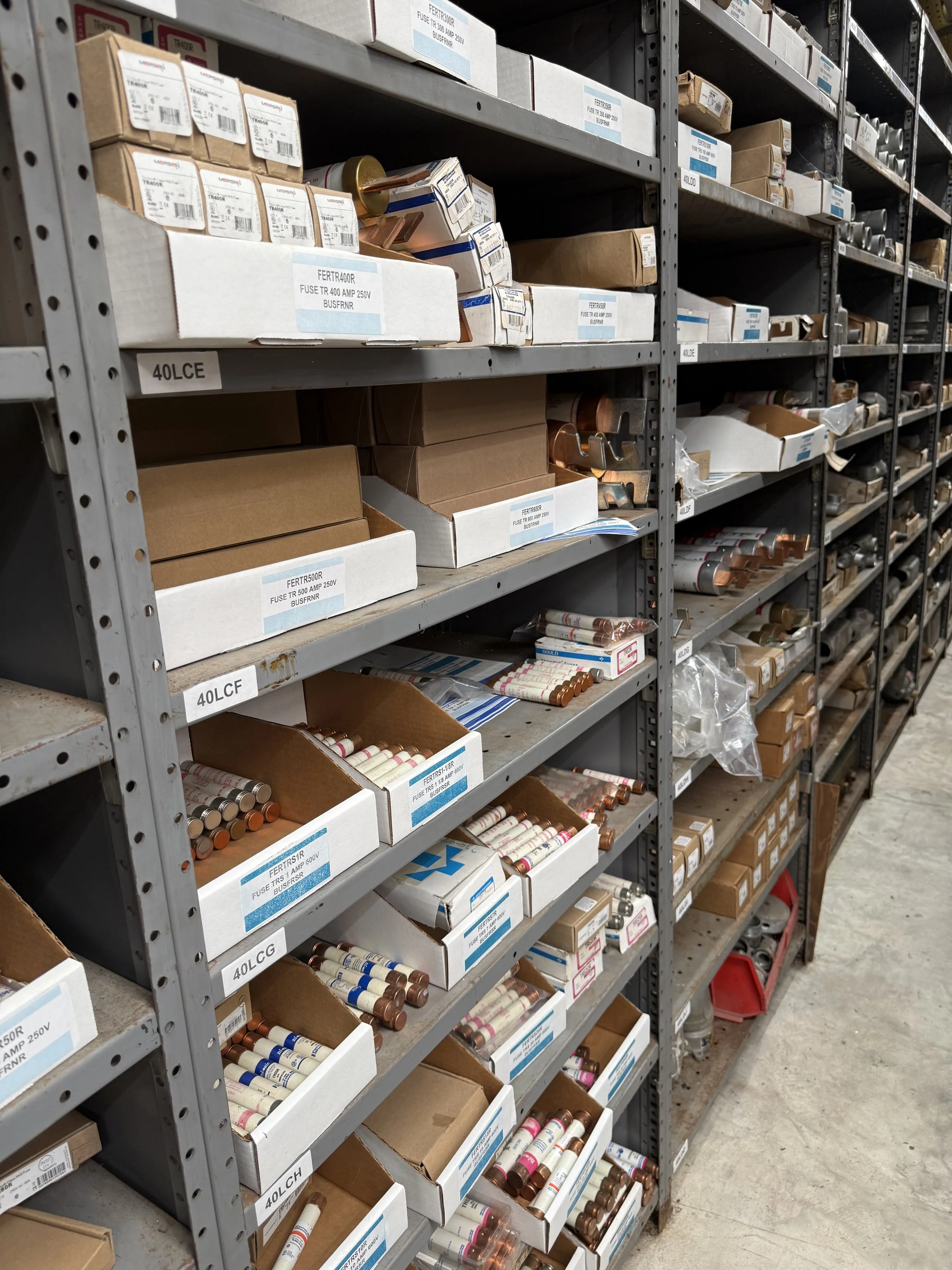 Shelves stocked with boxes of electrical fuses in a hardware store aisle.