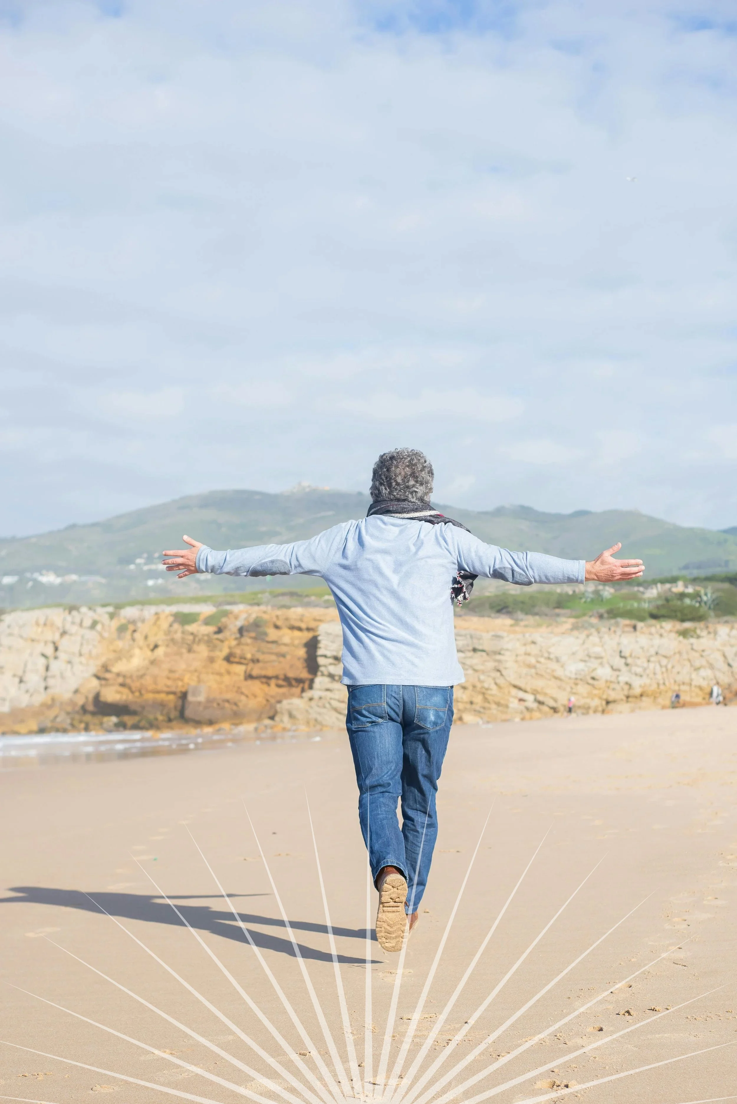 Older man walking on the beach with arms outstretched, facing away from the camera, downsizing and rightsizing your life to prepare for a move or simplify your home.