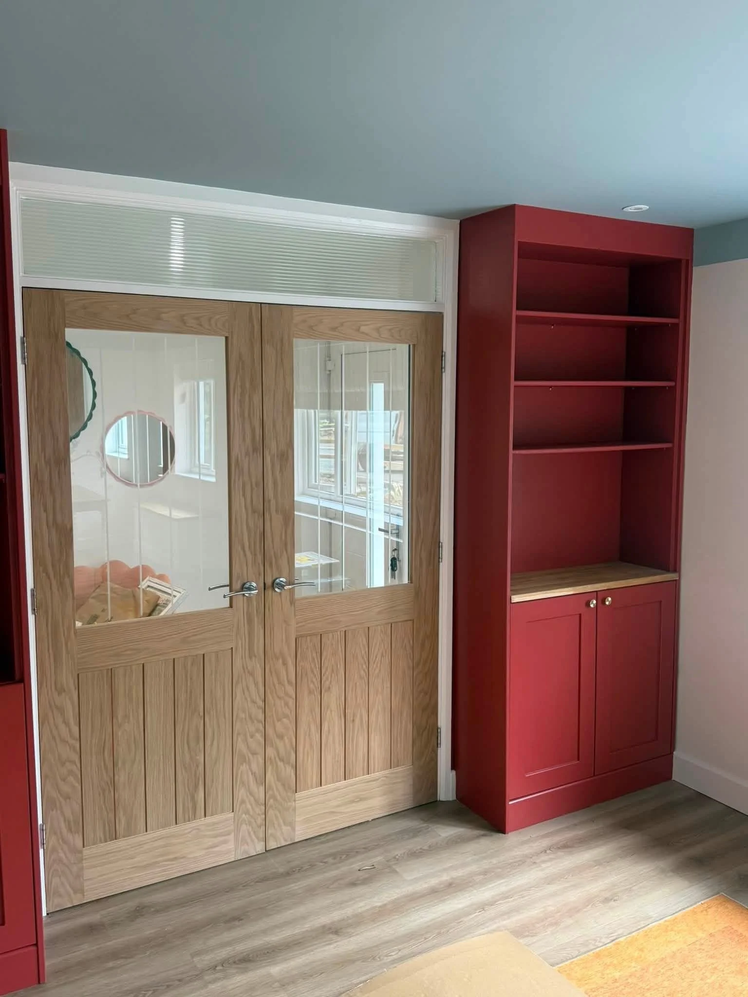 Red alcove shelving beside oak glazed doors