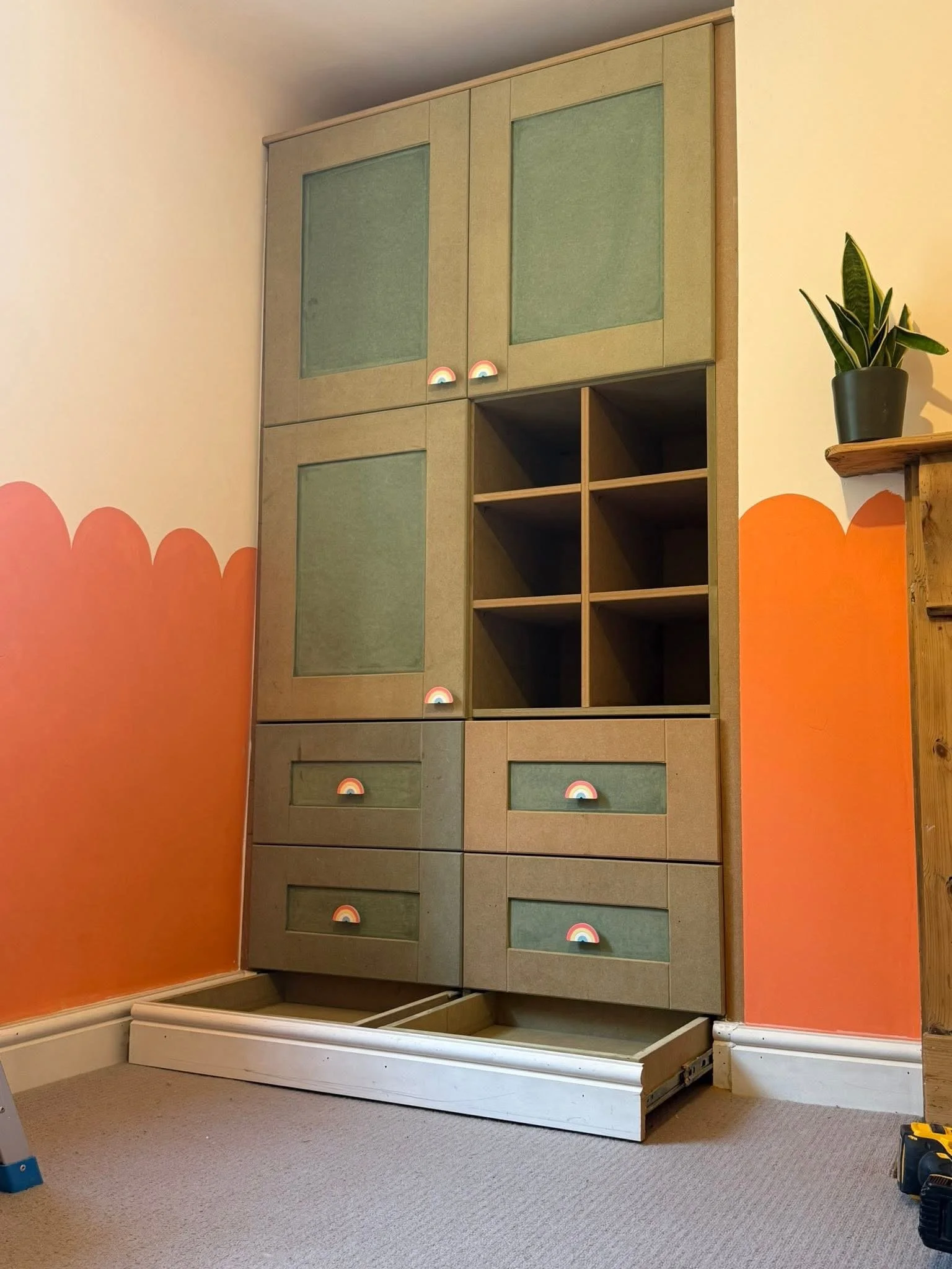 Bespoke green glazed display cabinet built into an orange scalloped wall
