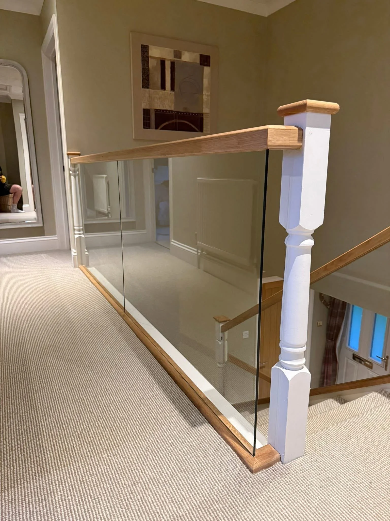 Glass landing balustrade with oak handrail and white newel post