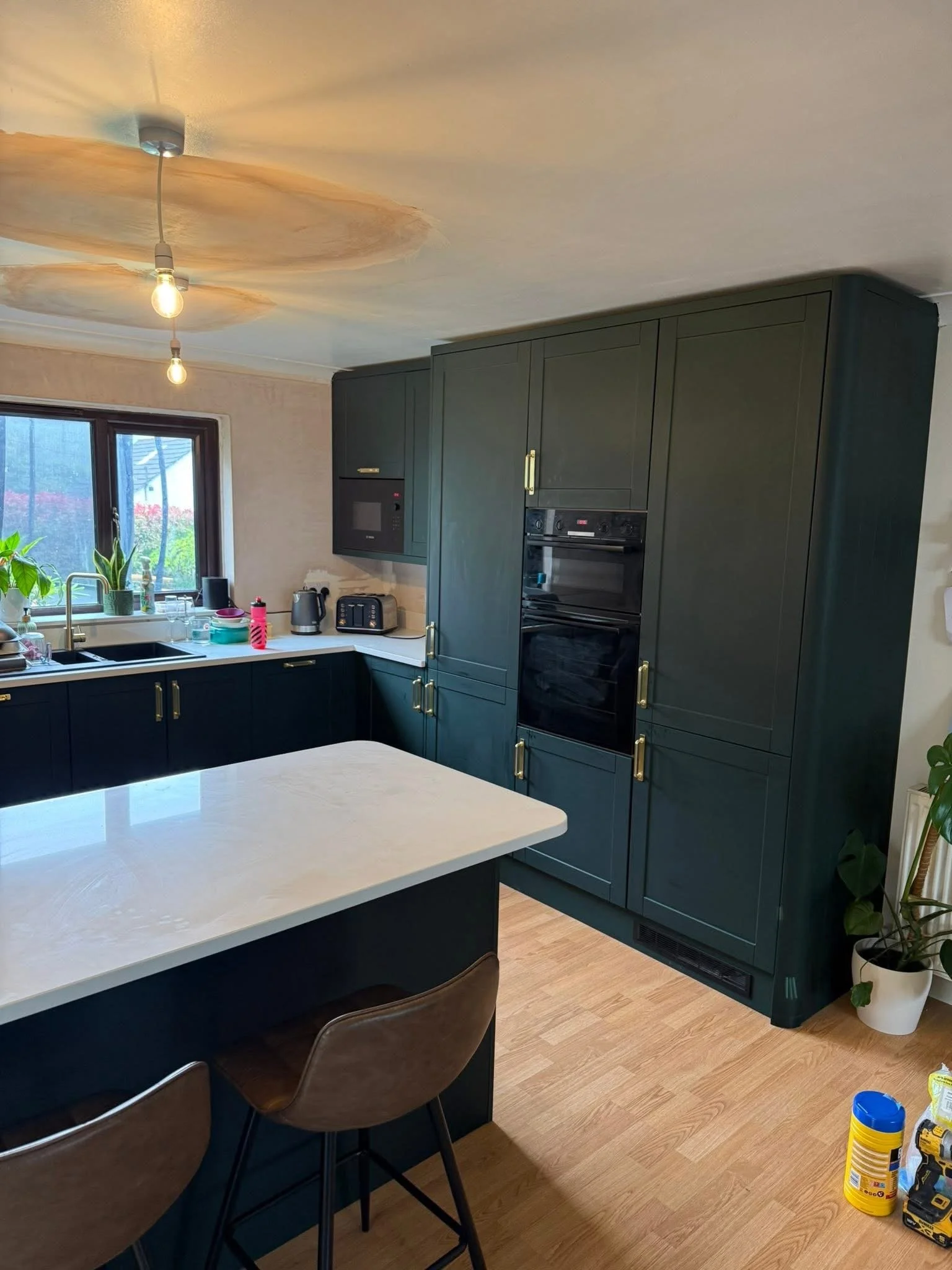 Dark green shaker kitchen with brass handles and island, fitted in Tavistock