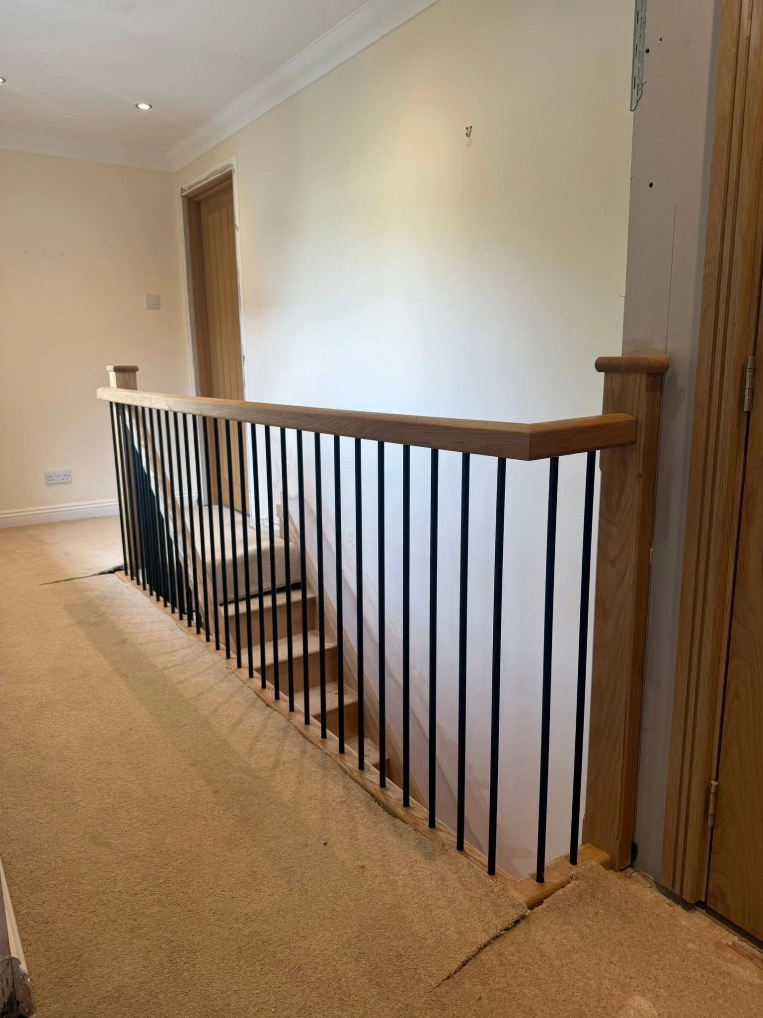 Black metal spindles with oak handrail around a stairwell