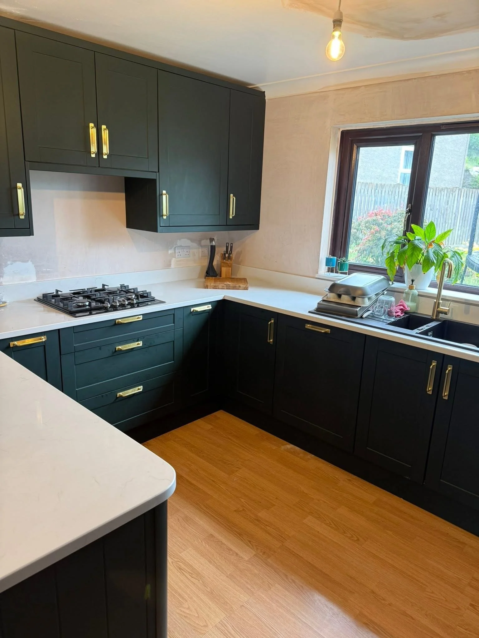 Dark green shaker kitchen units with quartz worktop and gas hob
