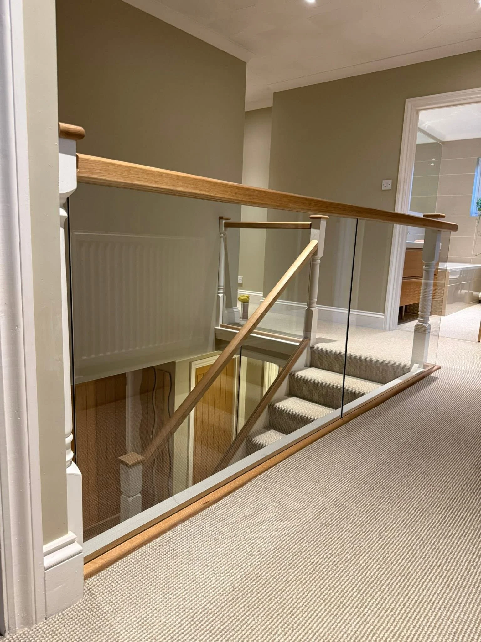 Frameless glass balustrade around a stairwell with oak capping