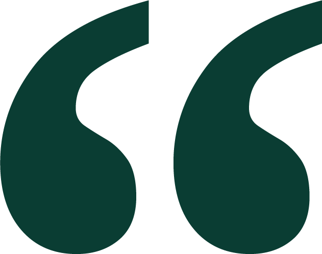 Close-up of two green quotation marks on a black background.