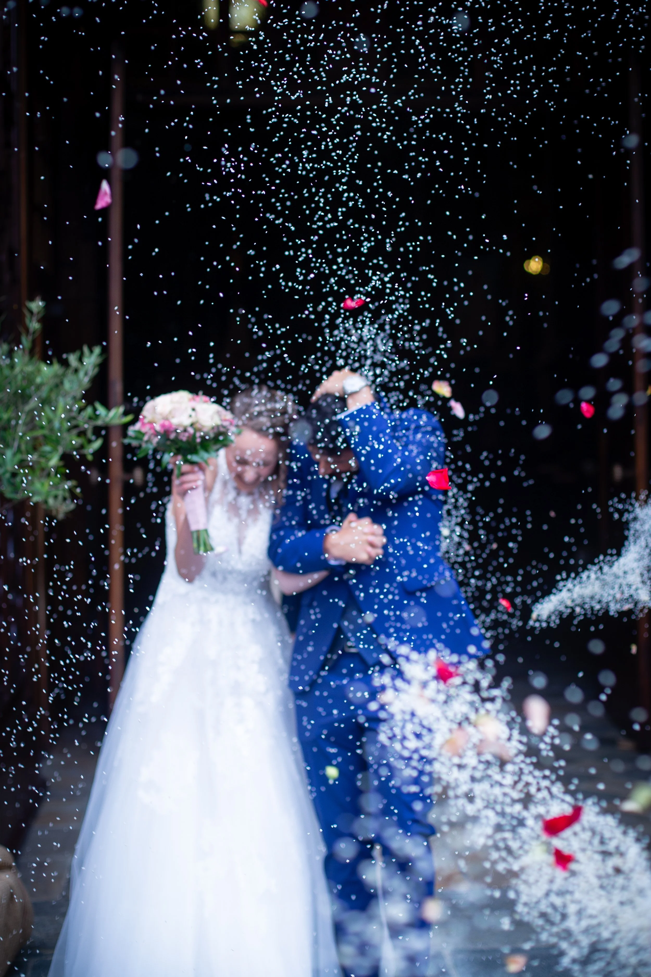 A bride and groom sharing a moment under confetti at their wedding celebration.