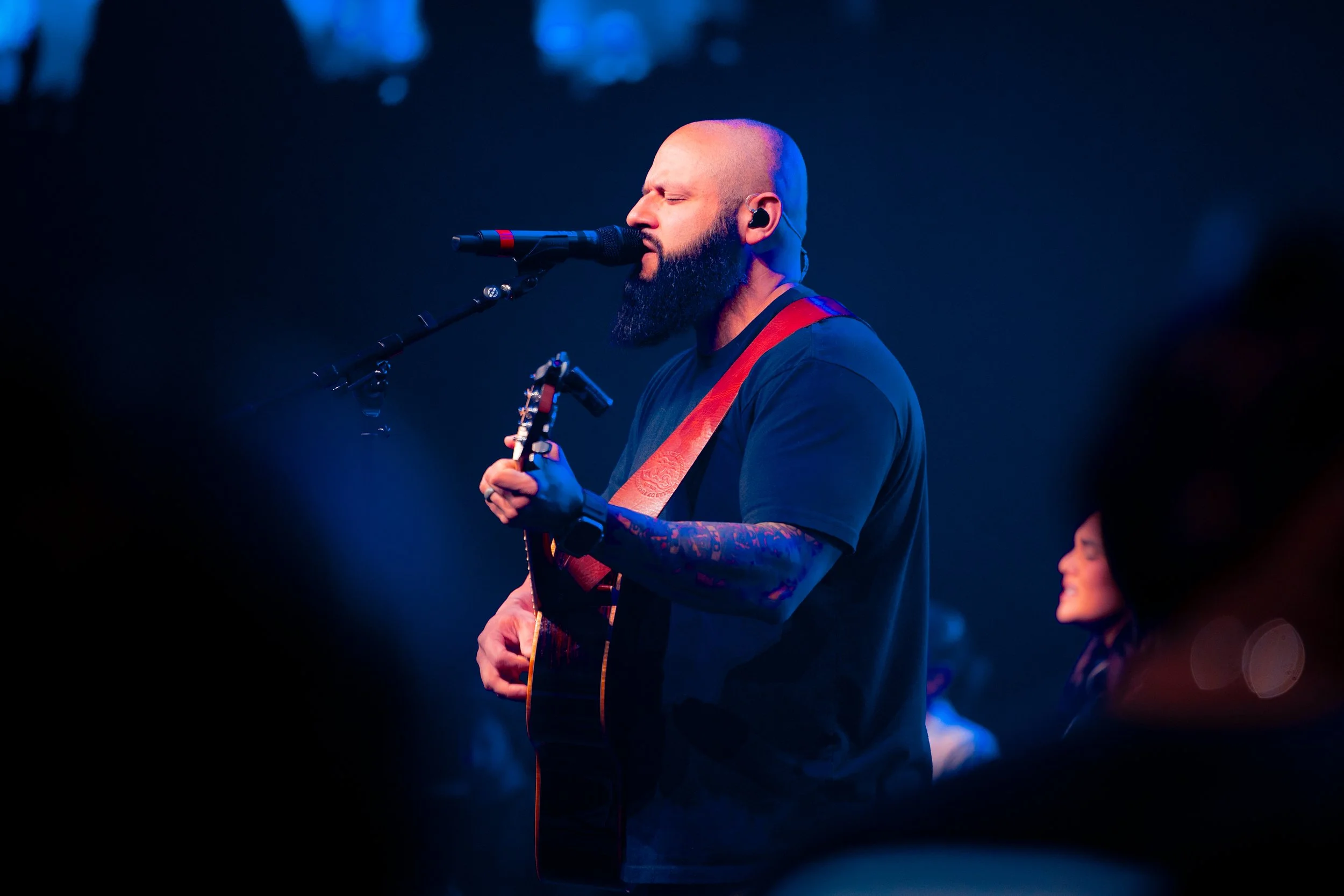 A black-and-white photo of eleven diverse people standing against a plain background, arranged in three rows, facing the camera.