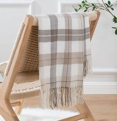 Living room design Inspiration featuring a stylish shoppable plaid throw blanket with beige, white, and gray stripes draped over a light wooden chair in a bright room.