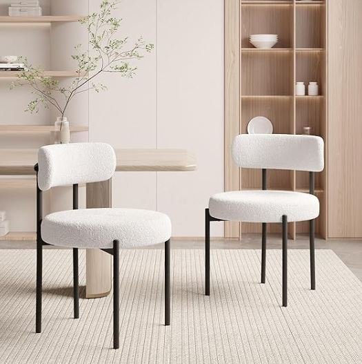 Dining room inspiration featuring a stylish shoppable minimalist dining area with two white upholstered chairs and a small wooden table, a neutral-colored rug, a shelf with a vase and plant,.