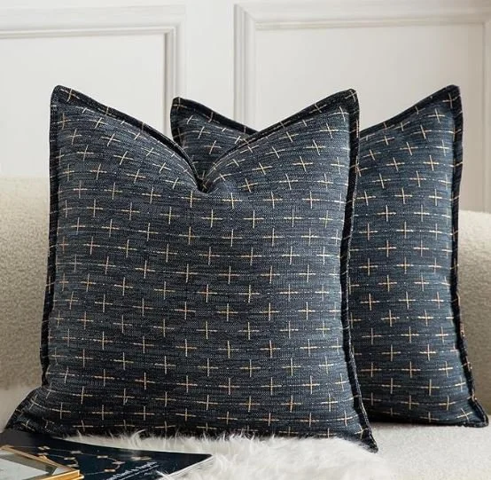 Living room design Inspiration featuring a stylish shoppable  navy blue decorative pillows with a cross pattern, placed on a white furry surface against white paneled walls.