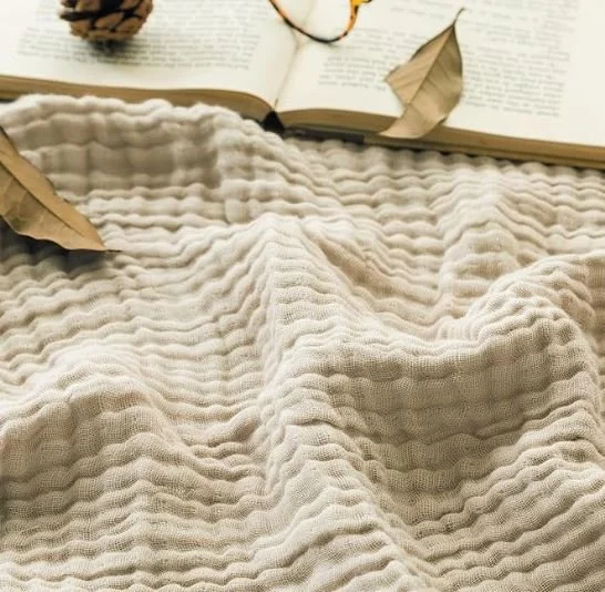 Bedroom design Inspiration featuring a stylish shoppable  beige textured blanket with an open book and dried leaves on top.