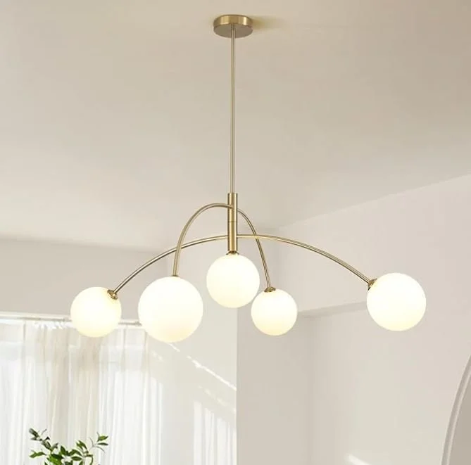 Interior design Inspiration featuring a stylish shoppable Modern chandelier with five frosted glass globes hanging from curved metallic arms in a minimalist living room.