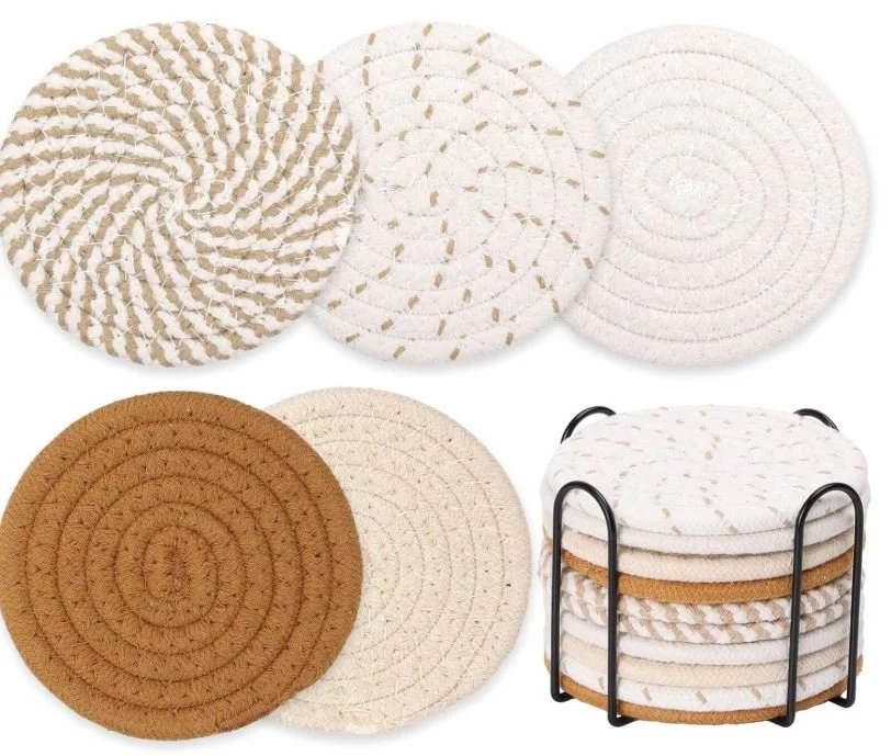 A collection of round, coiled, braided rugs or placemats in neutral colors, some stacked in a black wire rack.