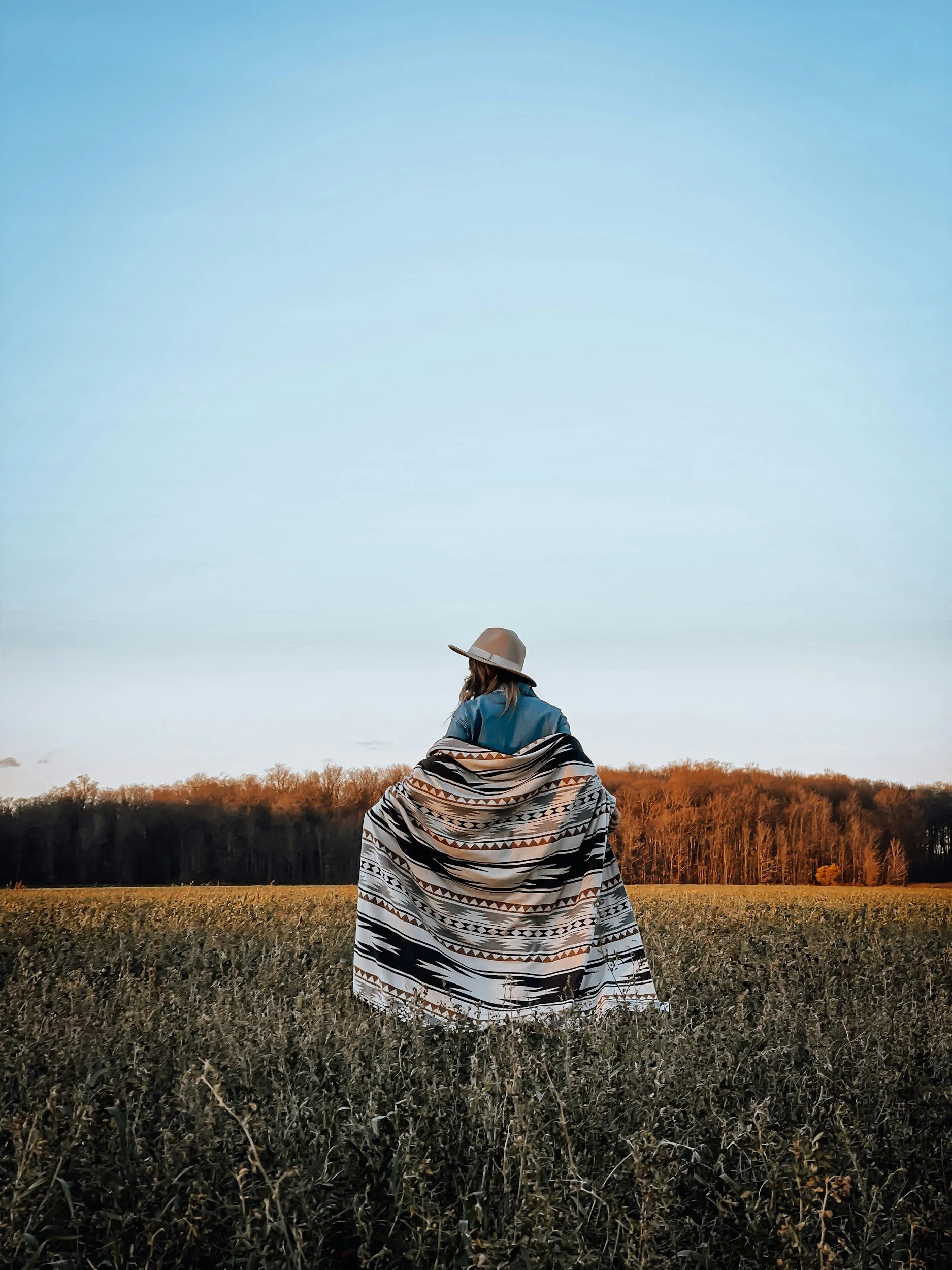 Person standing outside, with blanket around them, reflecting on the emotional weight of depression and the possibility of healing.