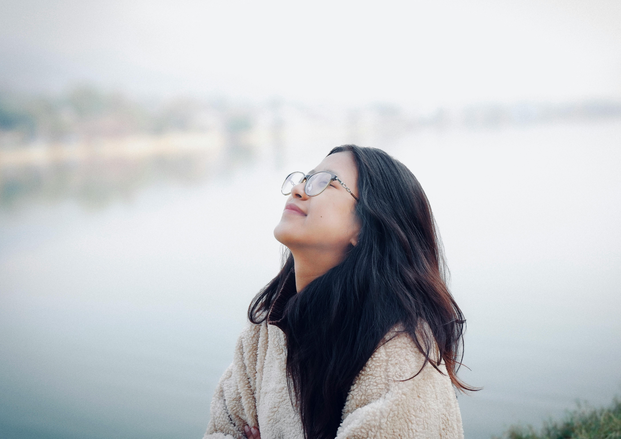 A  close-up of a person looking upward with a gentle, peaceful smile as they experience a moment of relief.