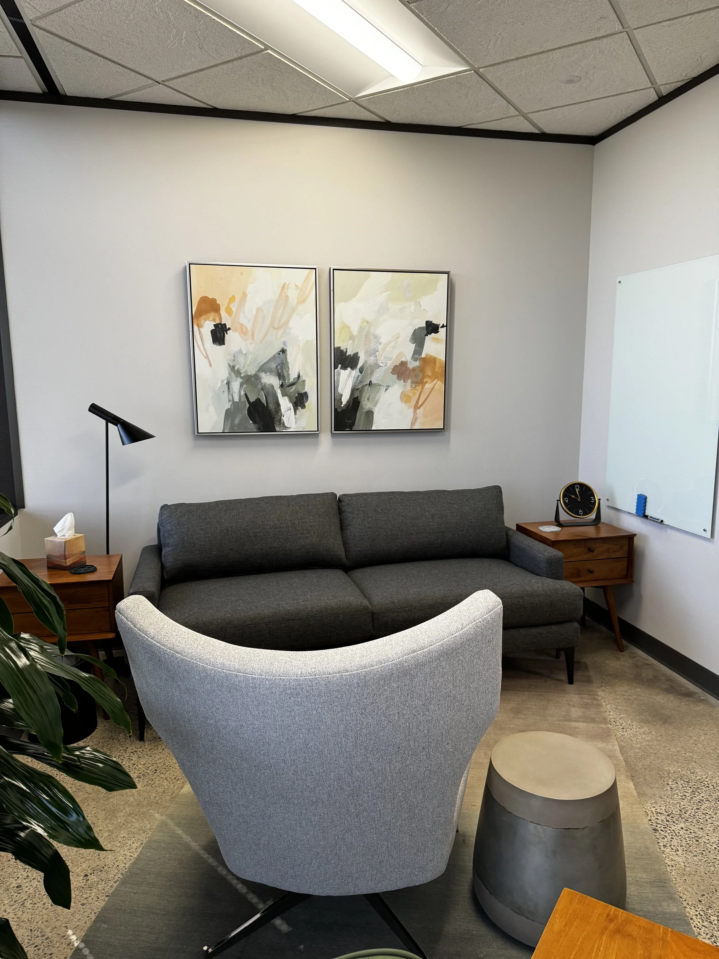 A private therapy office in The Heights, Houston.  The space is utilized by Daylily Therapy. It includes a dark grey couch and a light grey armchair.