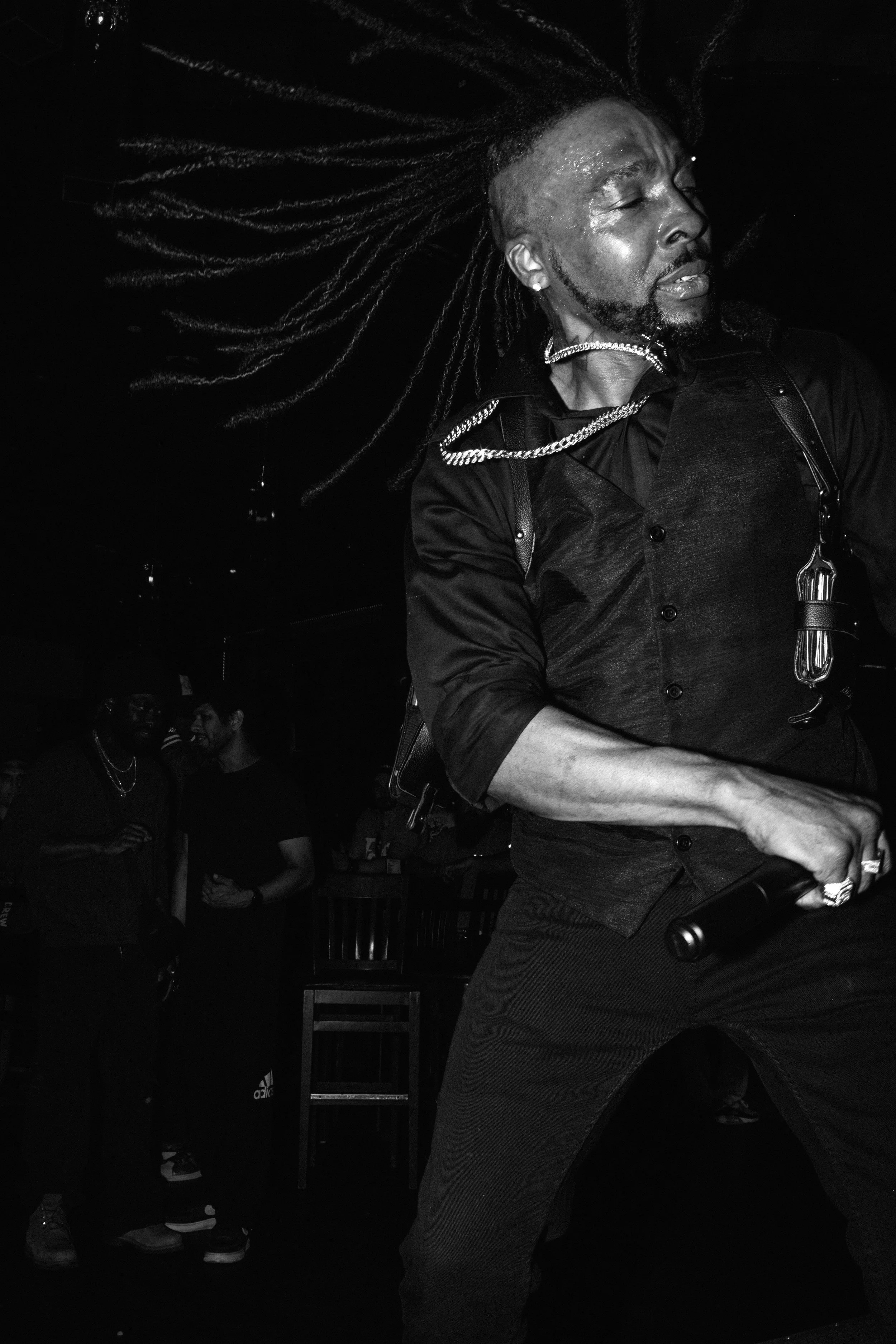 Mason Xross on stage with long dreadlocks dancing with eyes closed in a nightclub, with other people in the background.
