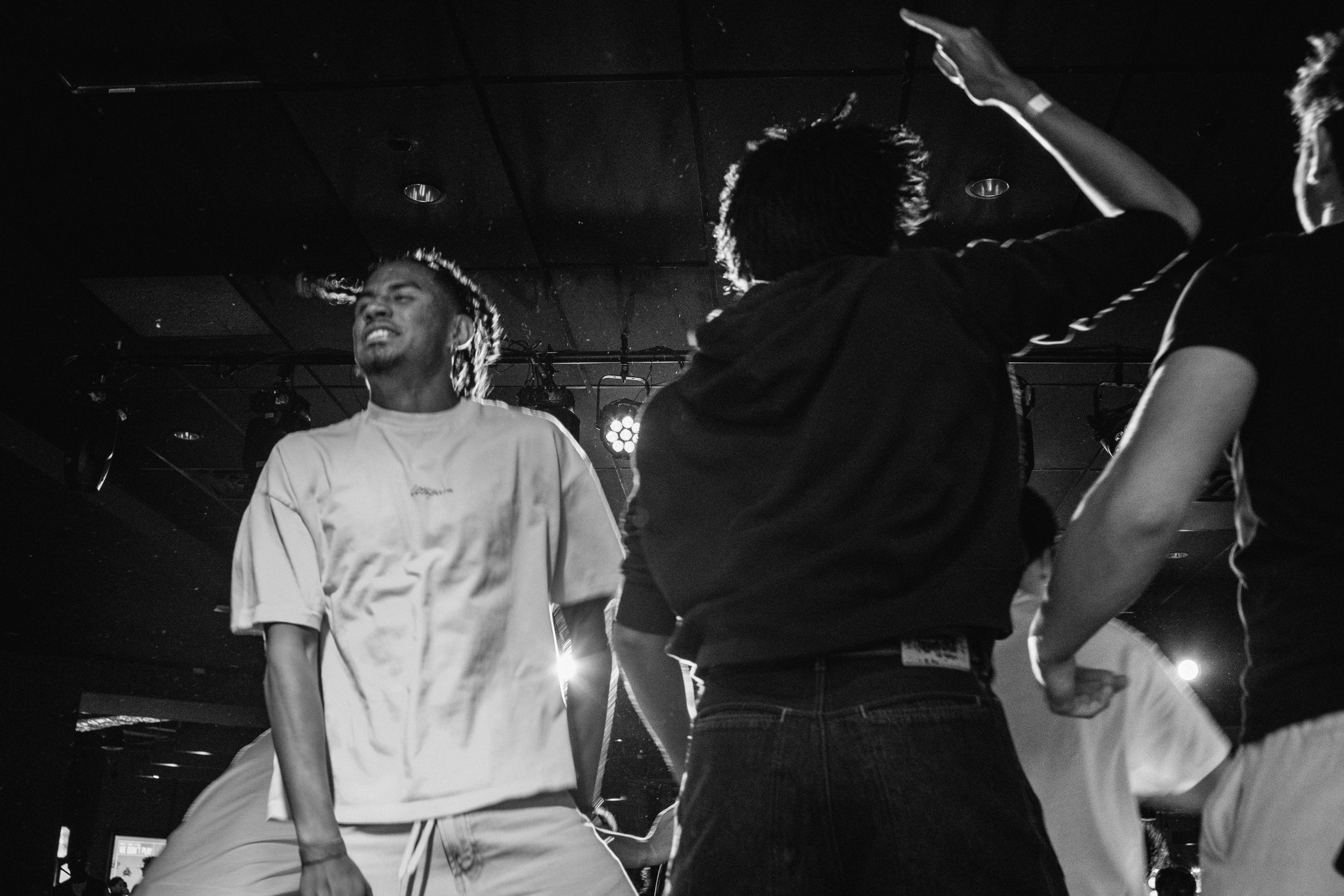 Group of young people dancing at a party or club, with lighting and a dark ceiling in the background.