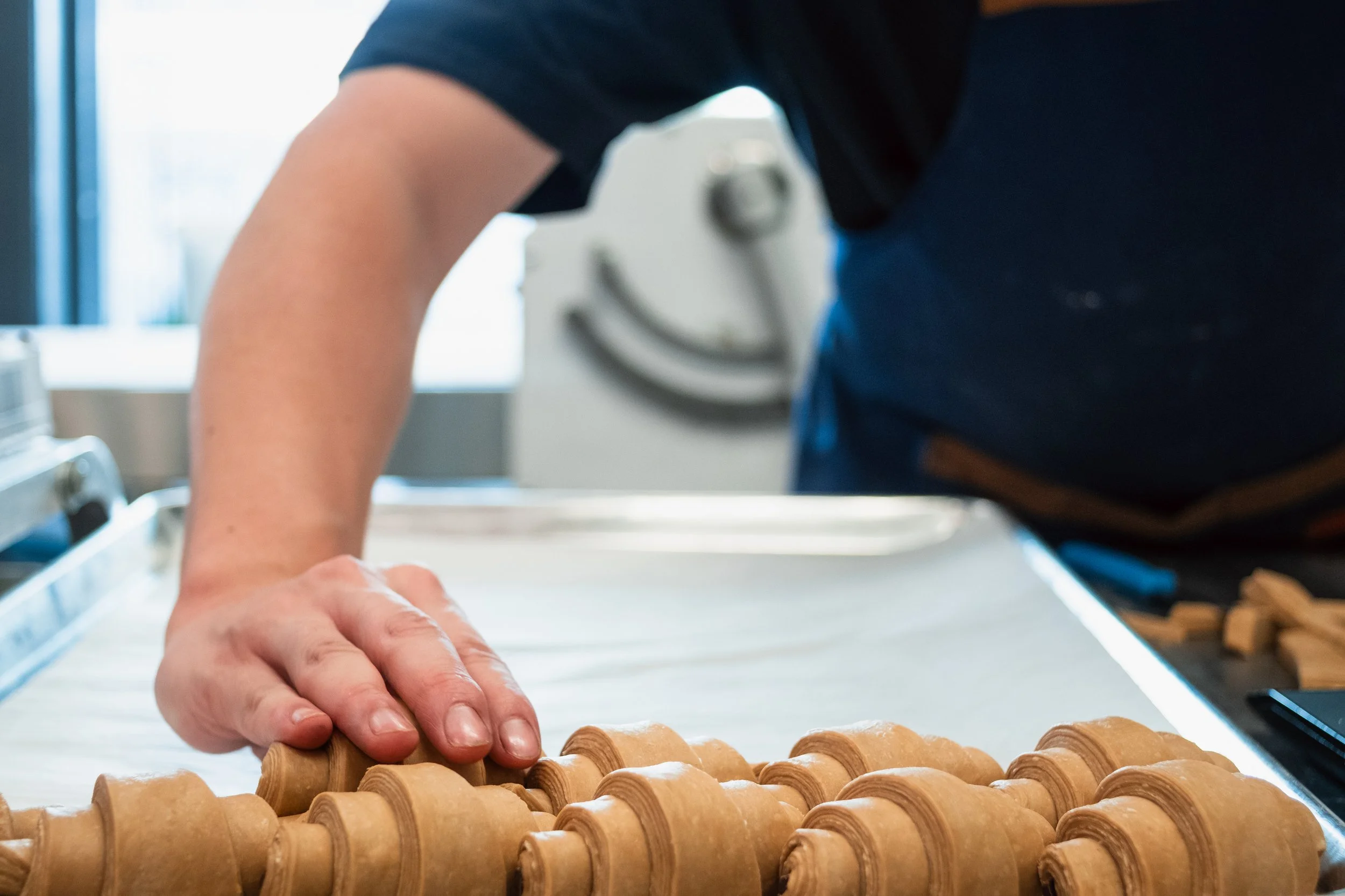 Placing Croissants on a sheet tray at Butterblock & Co in Calgary, AB. Photograph by Zachery Knudson. All rights reserved.