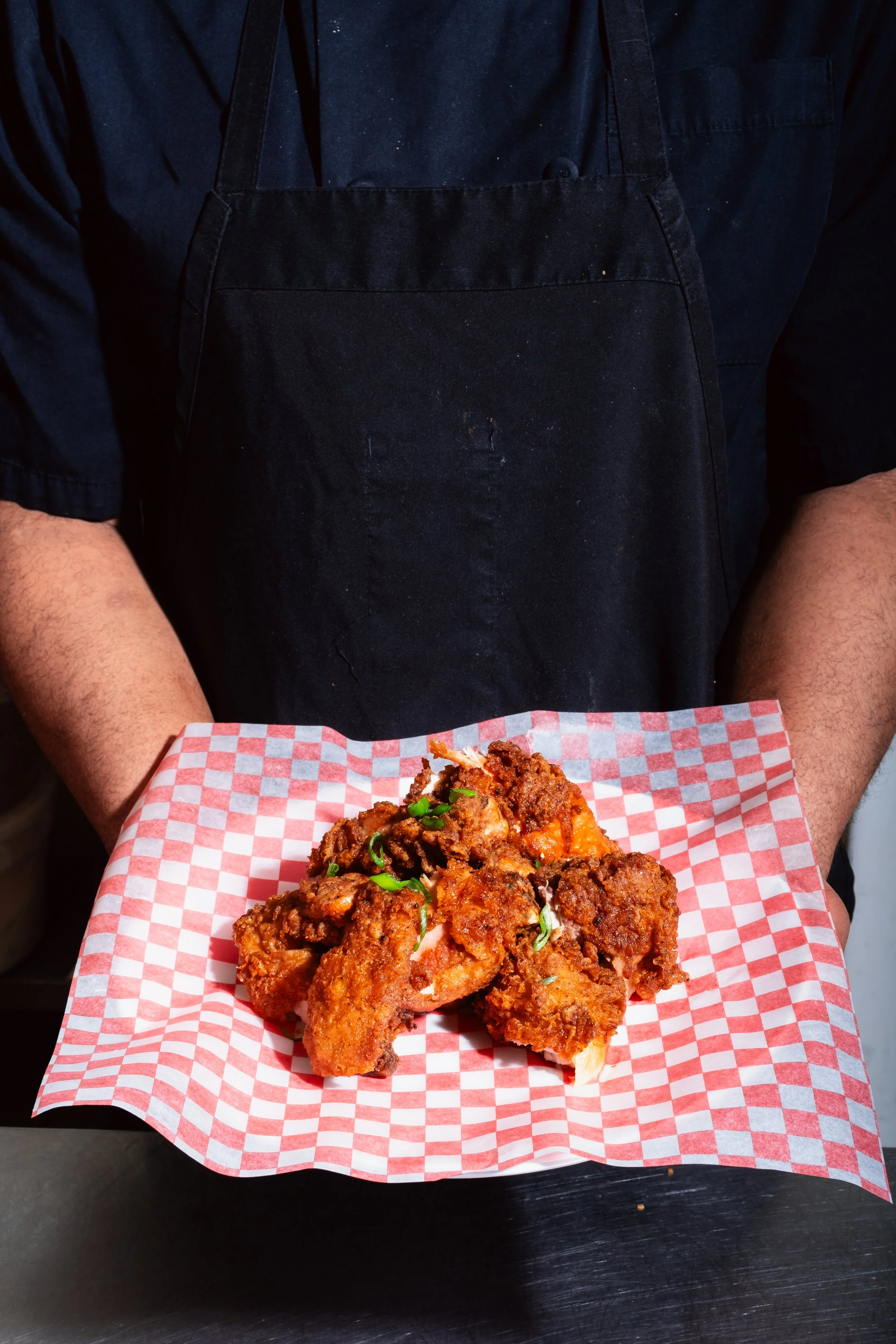 Photographer: Zachery Knudson. Chef Holding the Fried Chicken Plate. Business Banding Photography For King Solomon's Kitchen in Calgary AB