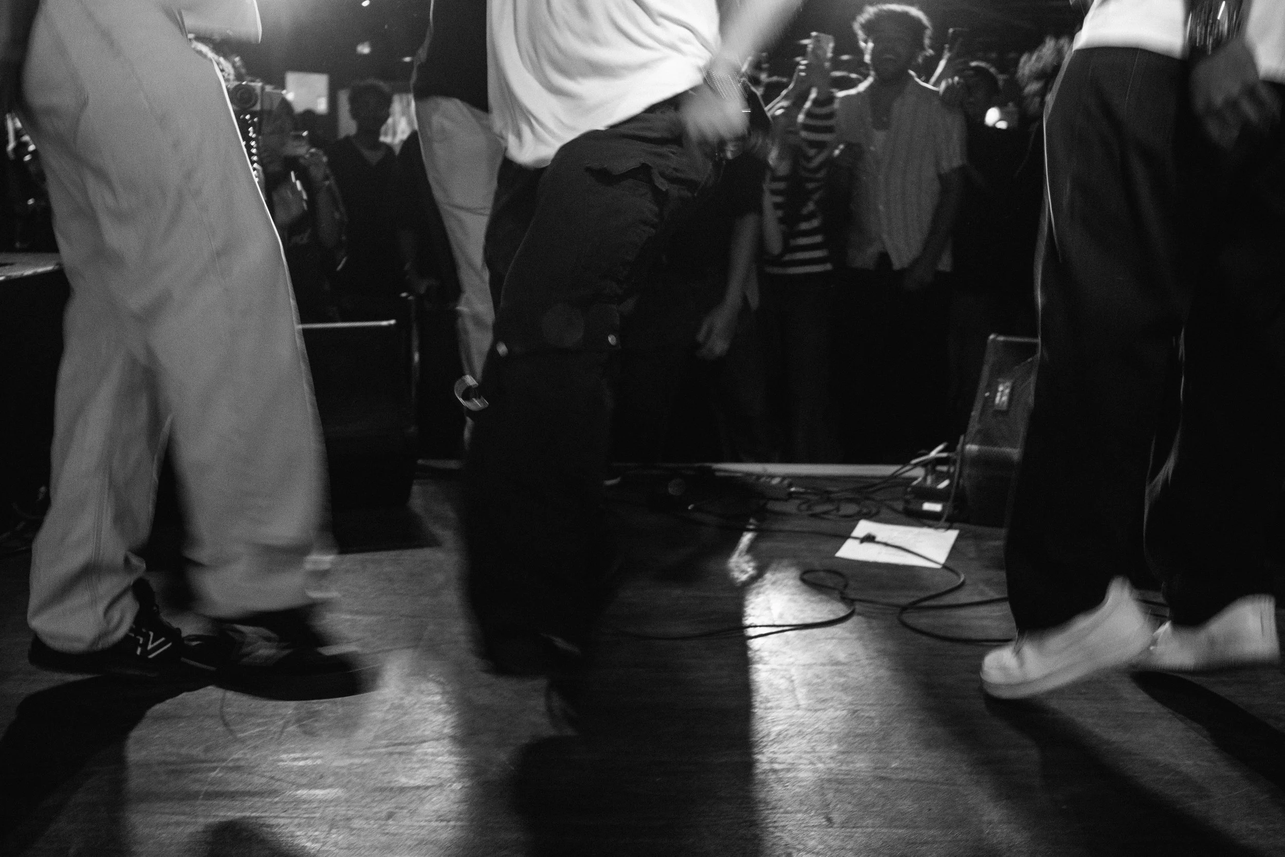 People dancing and moving in a nightclub or party setting, with some holding drinks in their hands, and a crowd in the background.