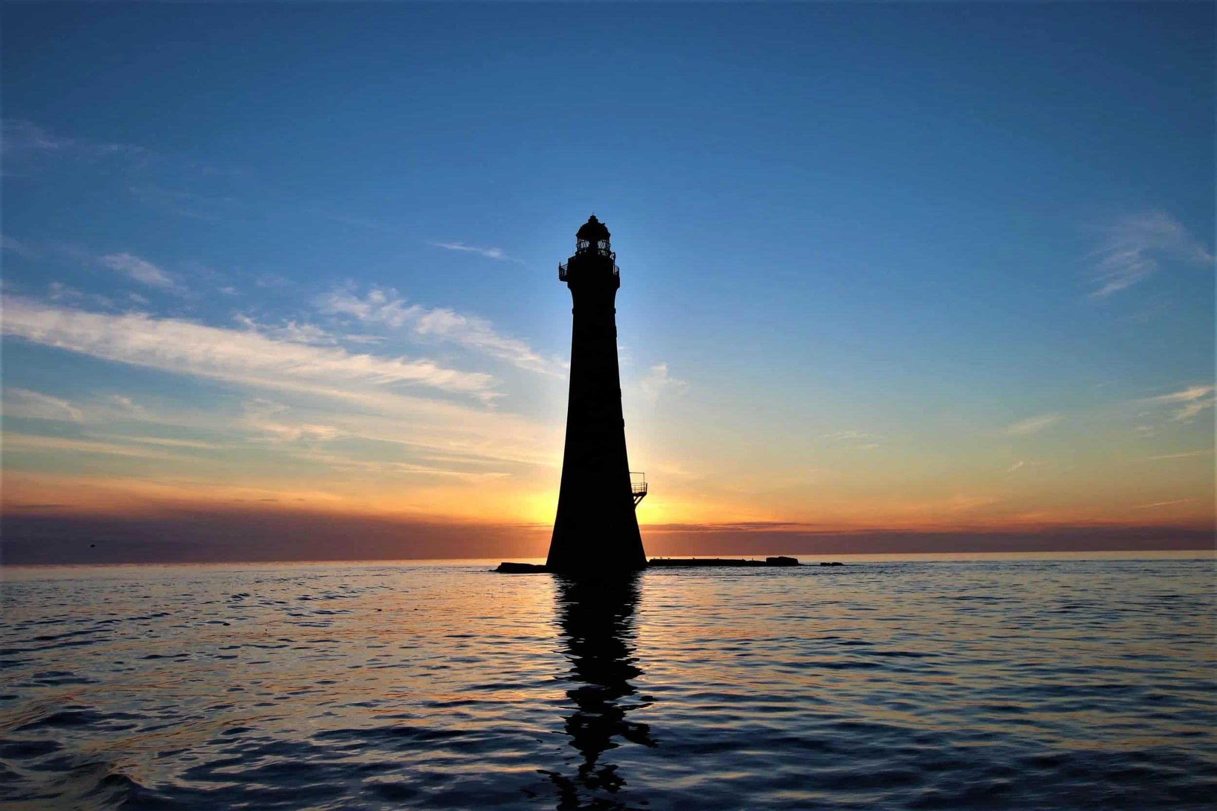 An image of a lighthouse on the Isle of Man at sunset.