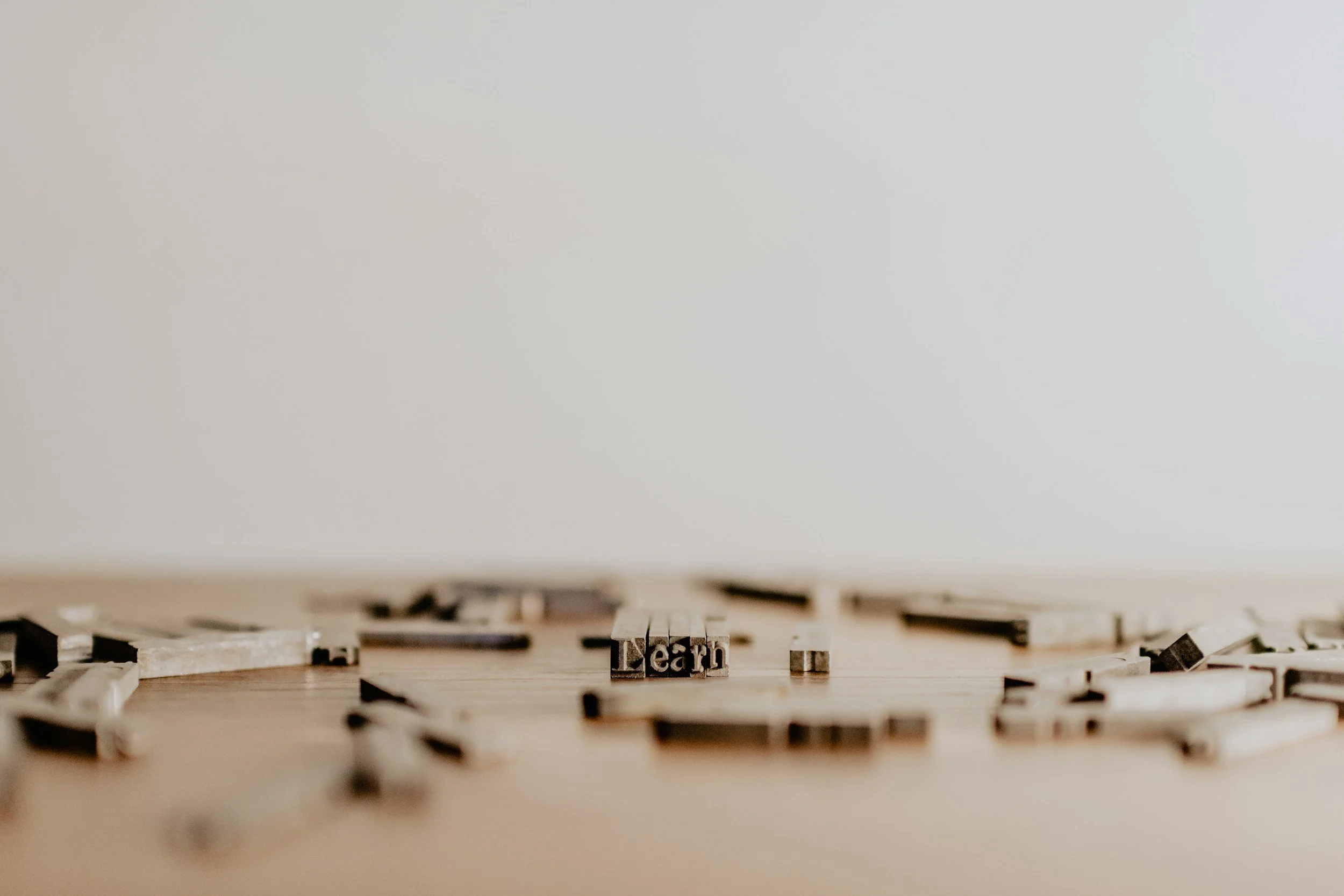 Close-up of scattered letter tiles spelling the word 'learn' on a wooden surface.