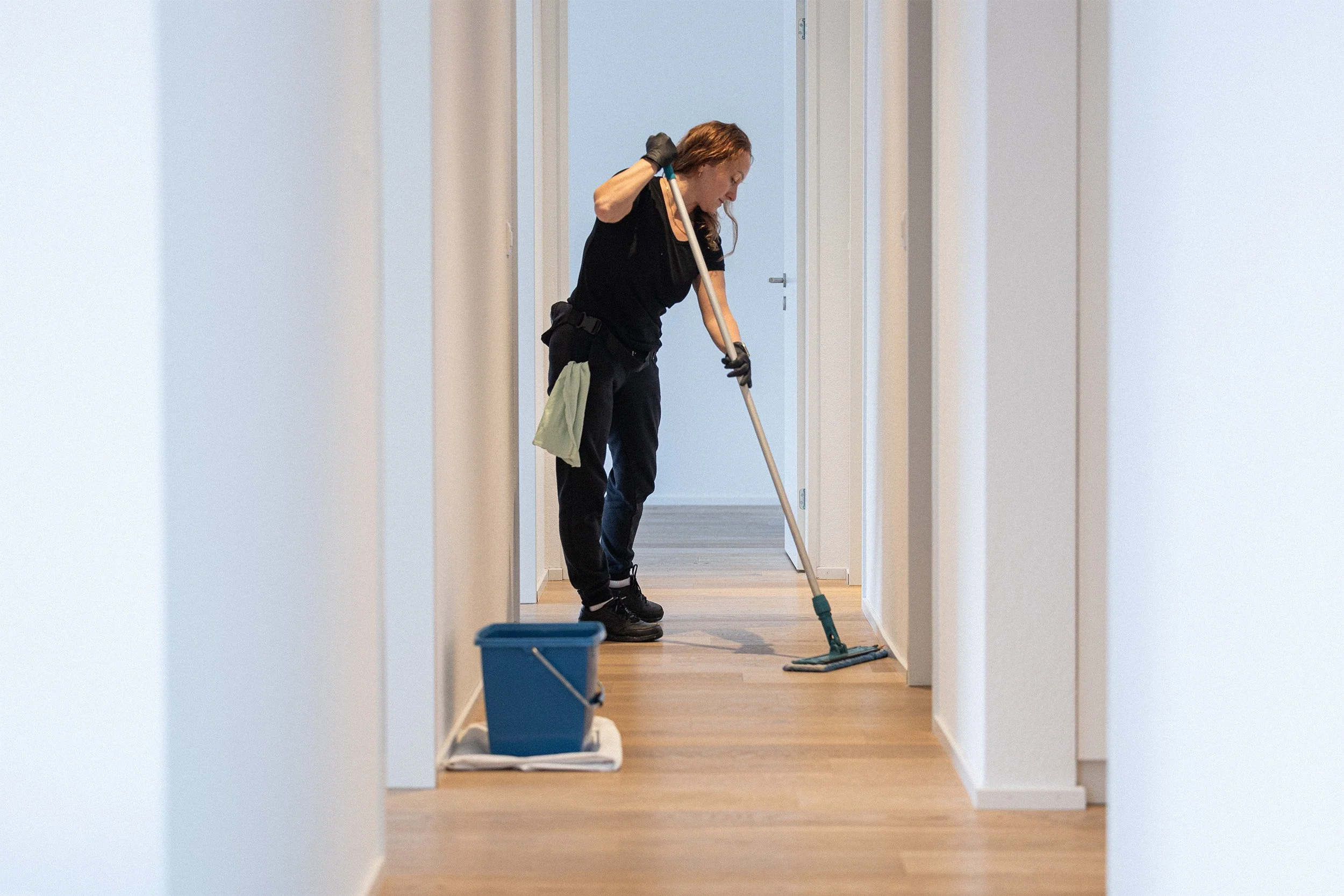 Eine Frau reinigt einen Flur mit einem Mopp.