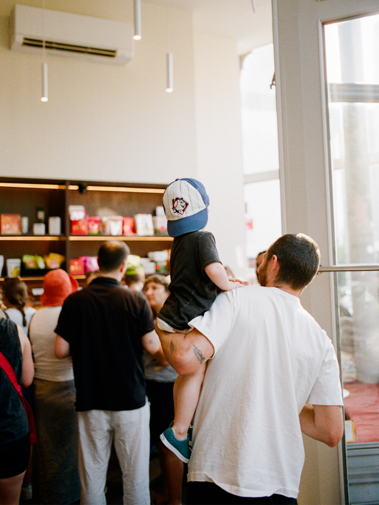 A man holding a young child on his shoulder inside CANDOR Candy.