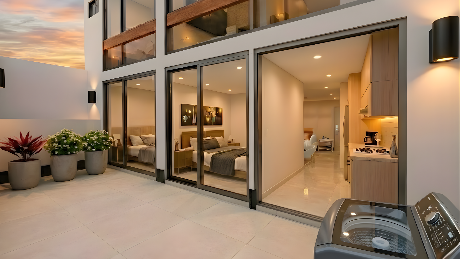 Modern apartment with glass doors leading to bedroom and living area, potted plants on balcony, washer in foreground.