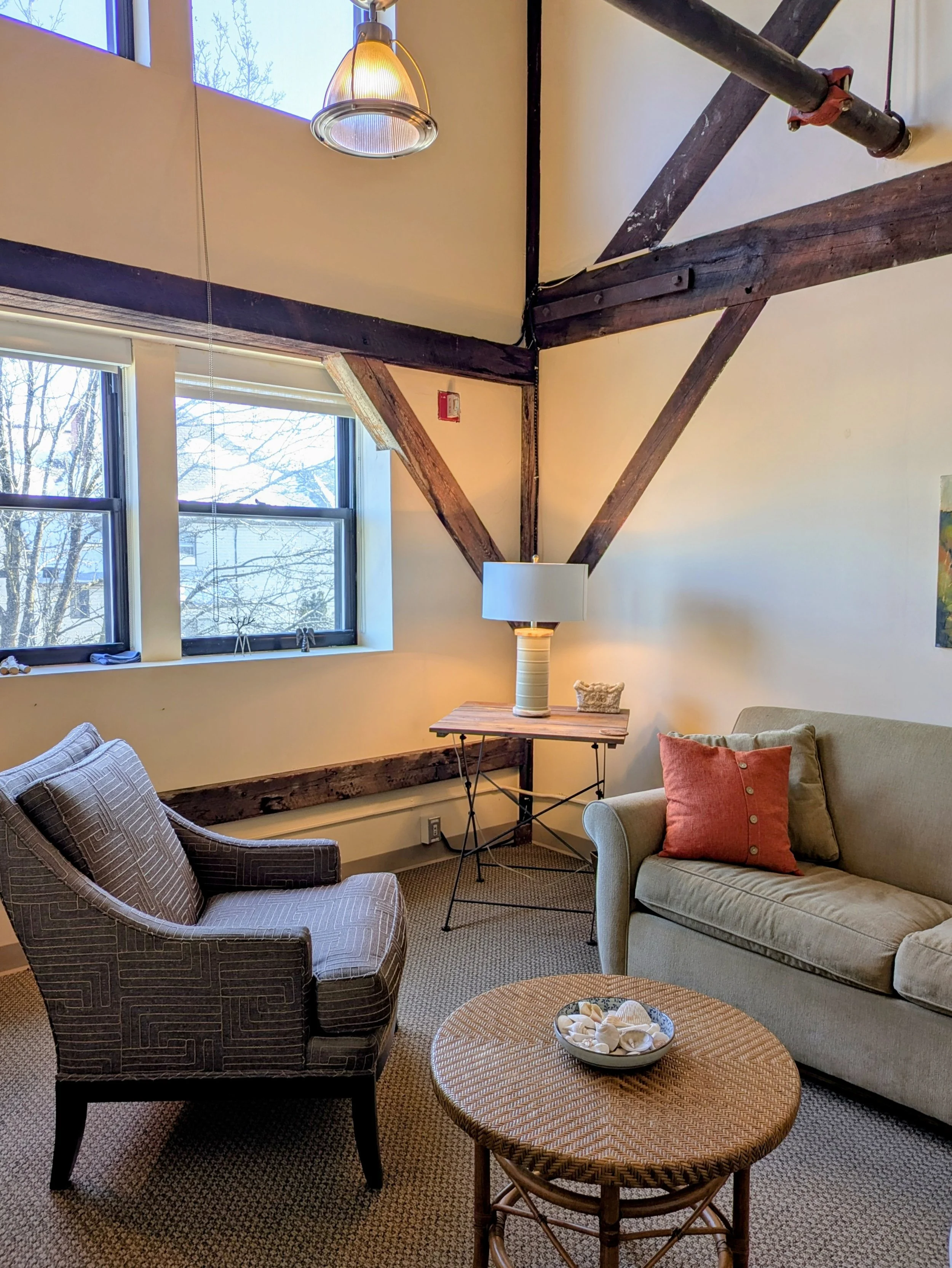 calm office space with natural light, couch, armchair, table, and lamp