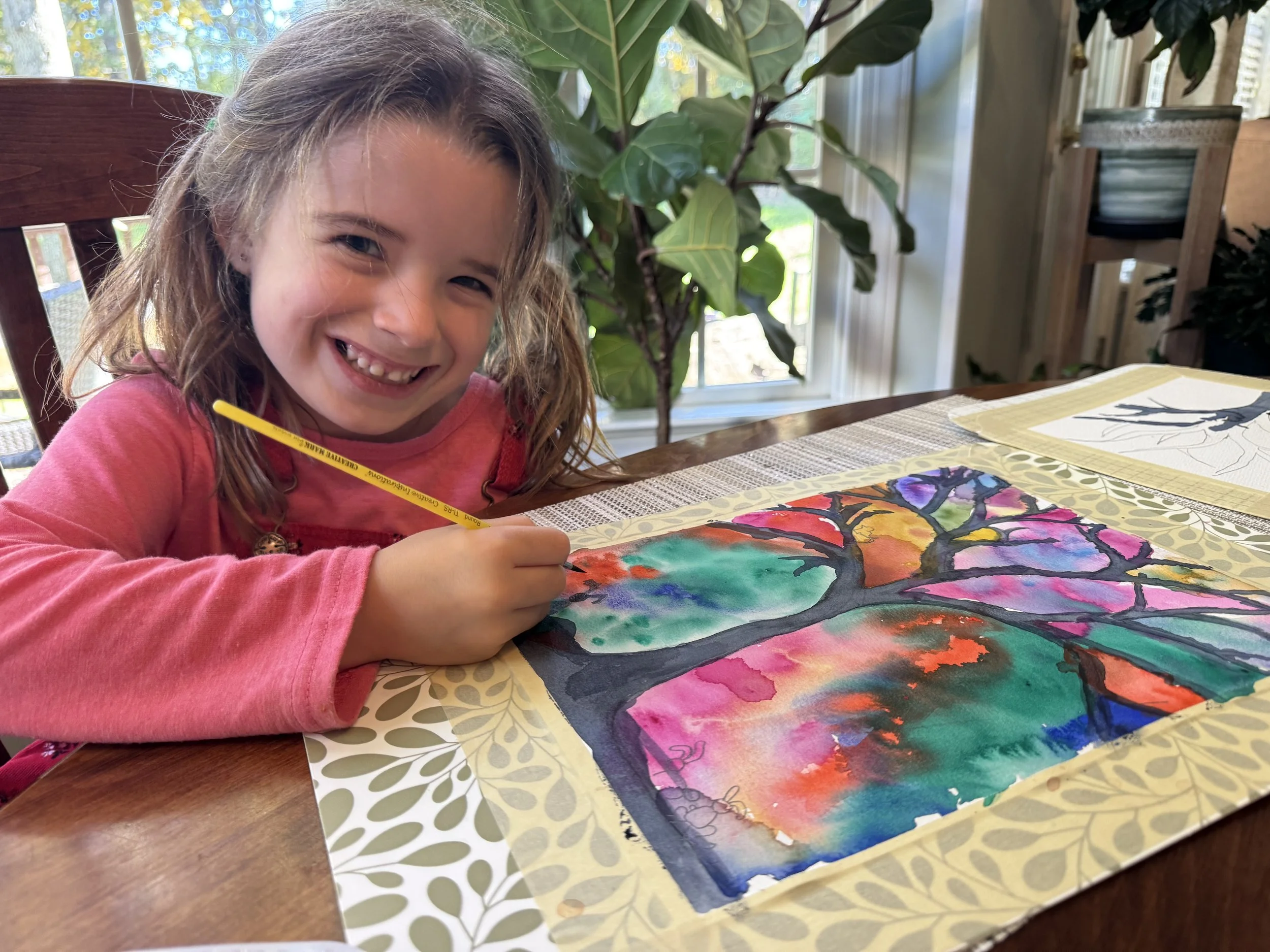Young girl painting tree with brightly colored background in watercolor