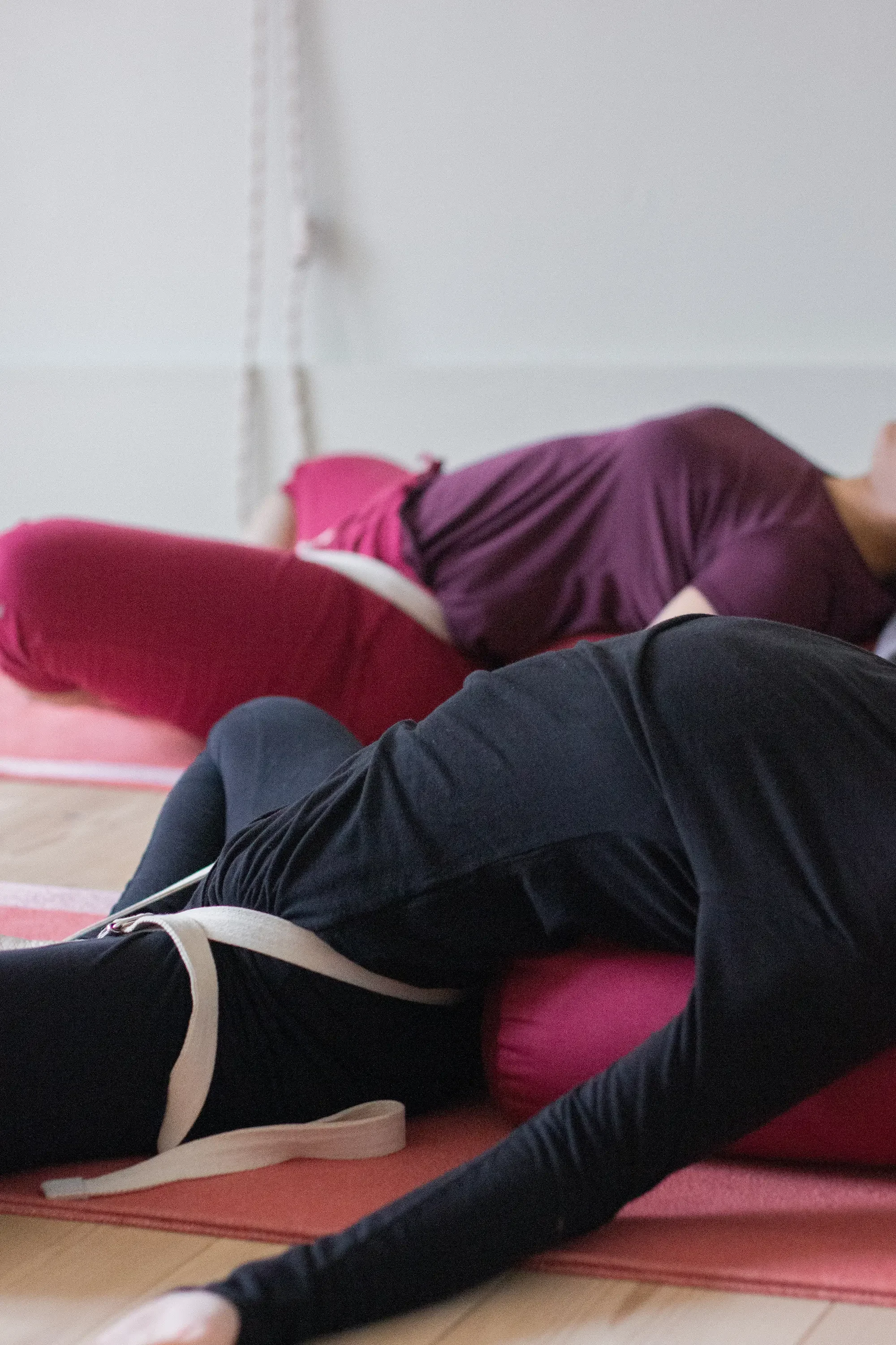 Zwei Personen liegen auf Yogamatten und führen Dehnübungen oder Übungen aus.