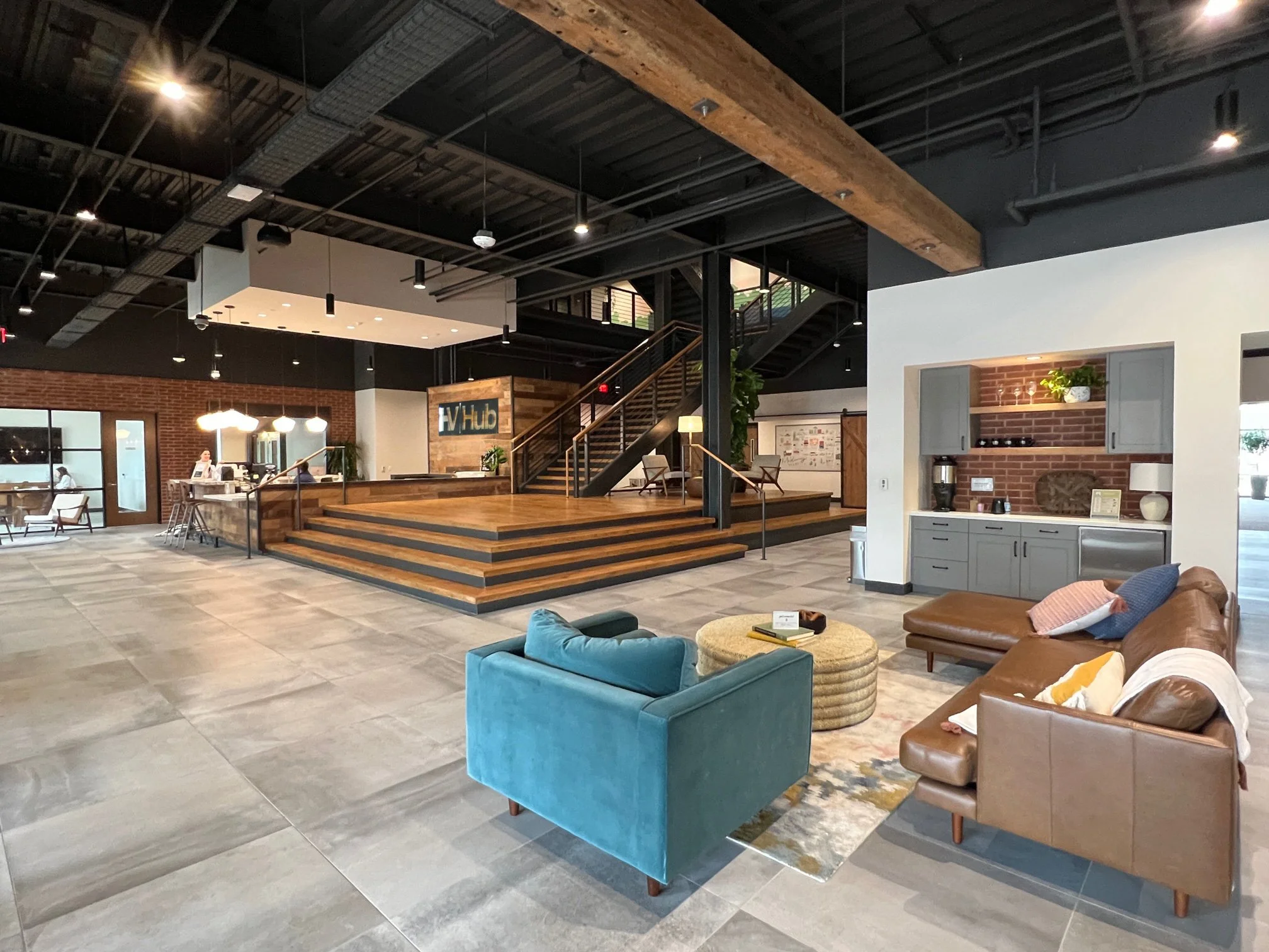Interior of a modern lobby with seating area, staircase, and hospitality counter.
