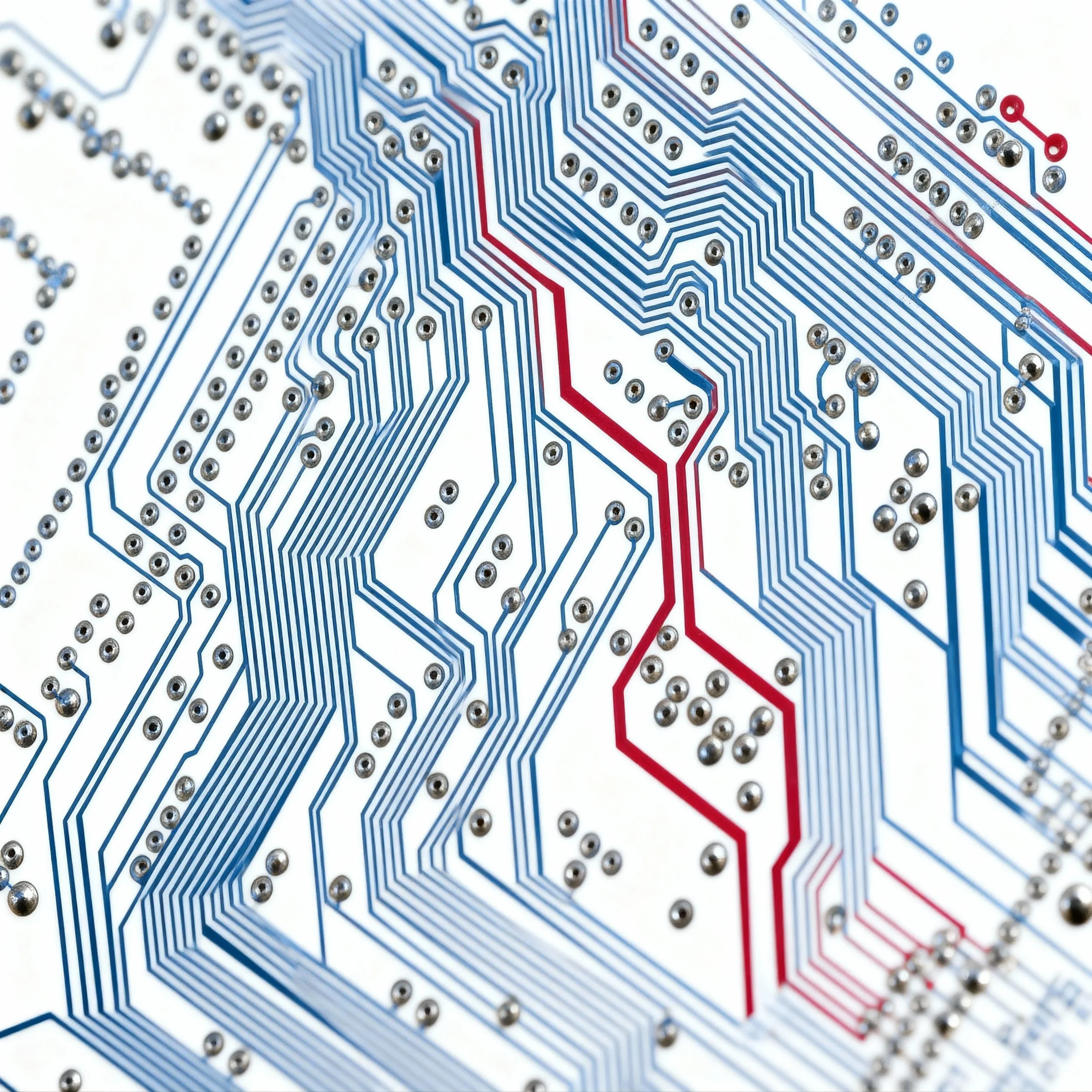 Close-up of a printed circuit board with blue and red electrical traces and metal solder points.