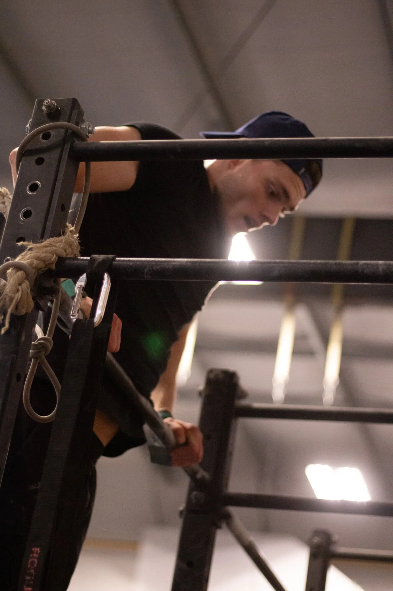 A man in athletic clothing with a backwards cap is working out, performing a push-up on a piece of gym equipment.