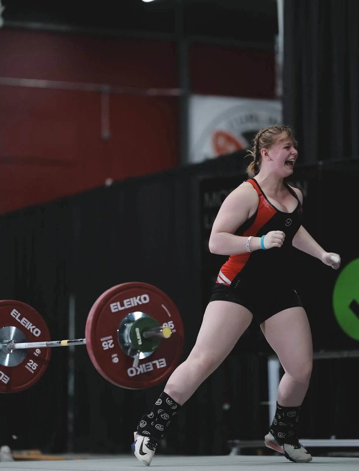 A female weightlifter celebrating after lifting weights at a competition.