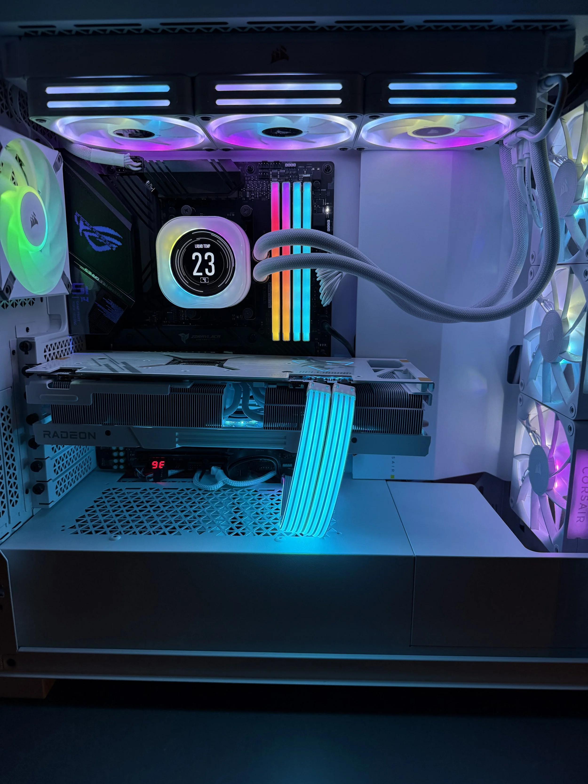 Inside a gaming computer with illuminated cooling fans, a liquid cooling system displaying temperature, and a graphics card.