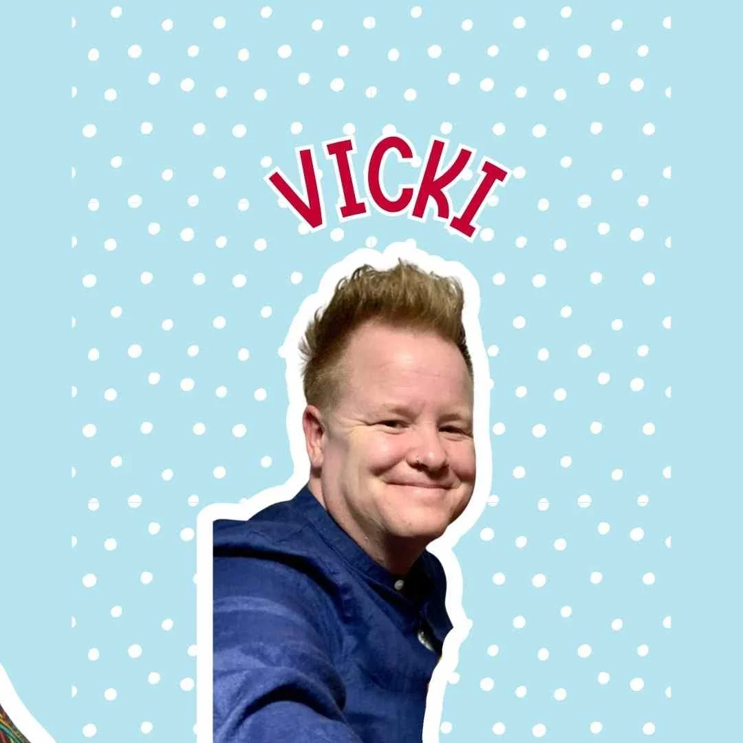 Close-up photo of a smiling man with short, curly blonde hair and wearing a dark blue shirt, behind a playful blue background with white polka dots. The name 'Vicki' is written in large red and white letters above his head.