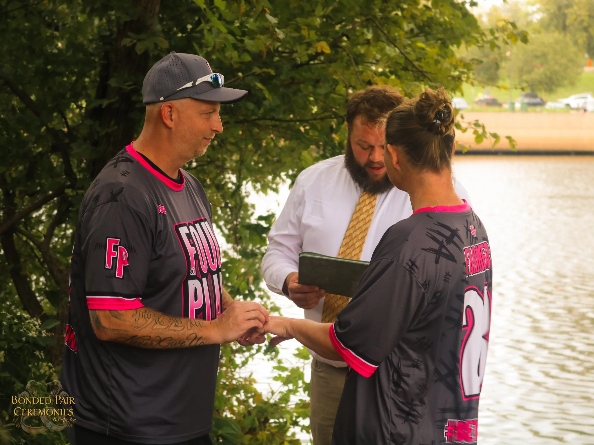A Man and Woman stand in golden light near the James River with a wedding Officiant
