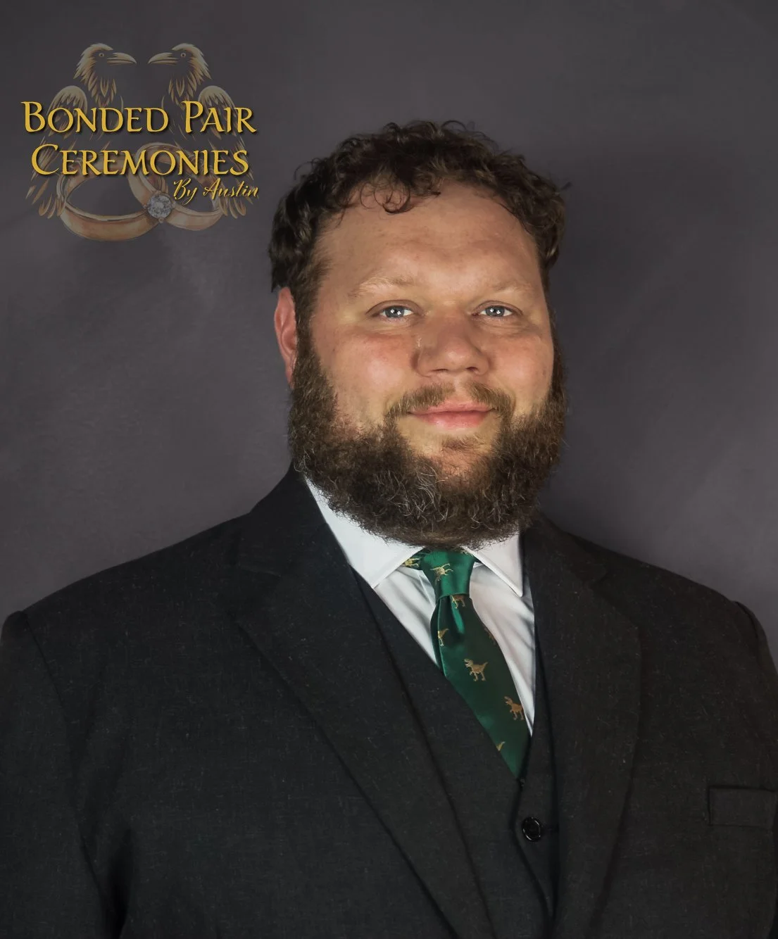 Man in a dark suit with a green tie featuring animal patterns, standing in front of a logo with two birds and rings, and the text 'Bonded Pair Ceremonies by Austin'.