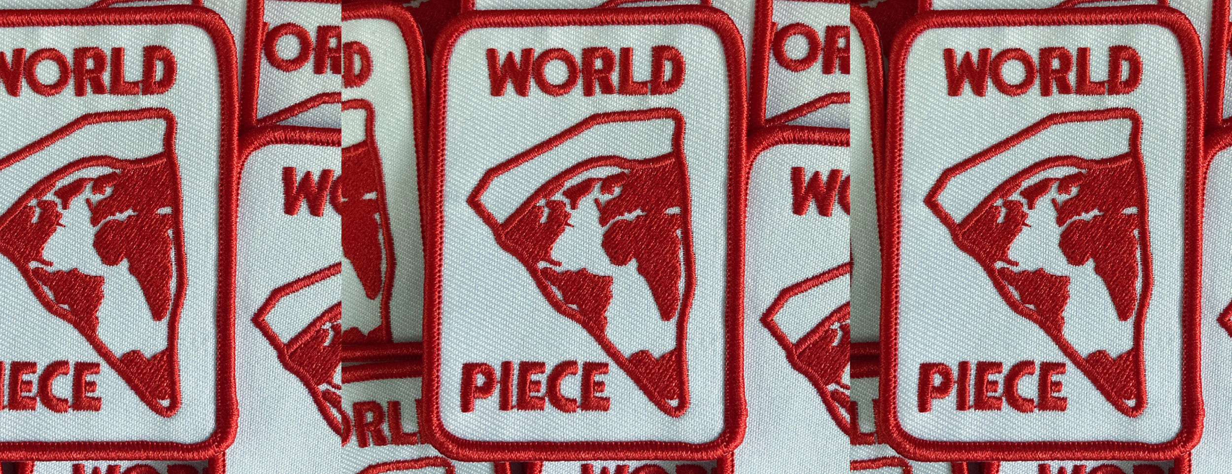 Multiple embroidered patches with a red border, featuring a map of the world and the words "WORLD PIECE" in red text.