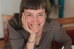 Mujer sonriendo, apoyando su cabeza con la mano