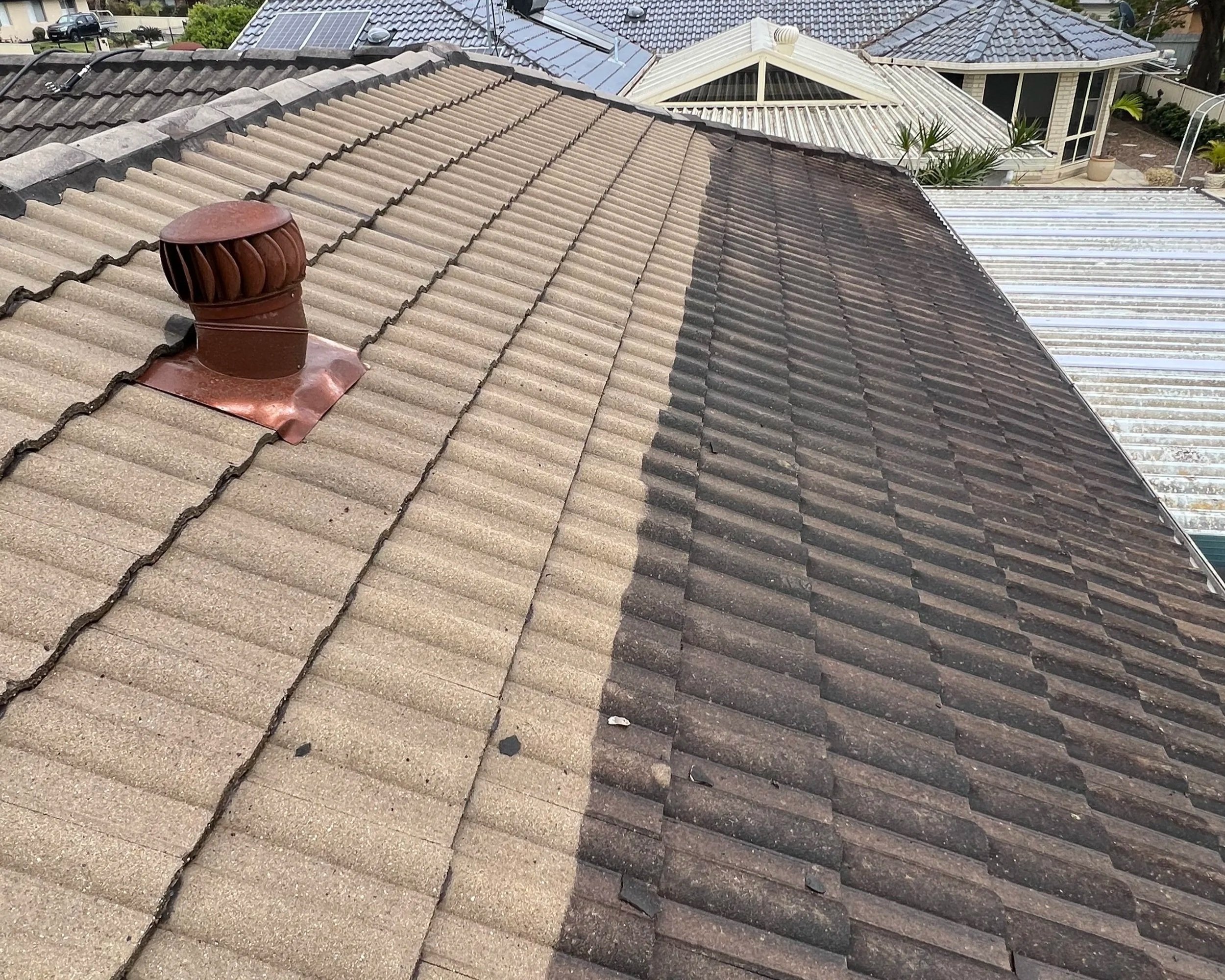 Comparison of a roof with beige and dark brown roof tiles showing a transition from old to new tiling.