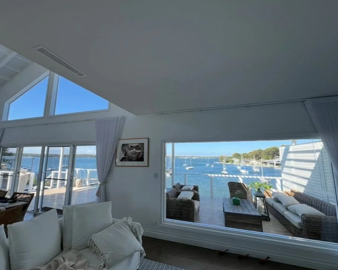 Living room with large windows and glass doors overlooking a waterfront with clean, clear windows