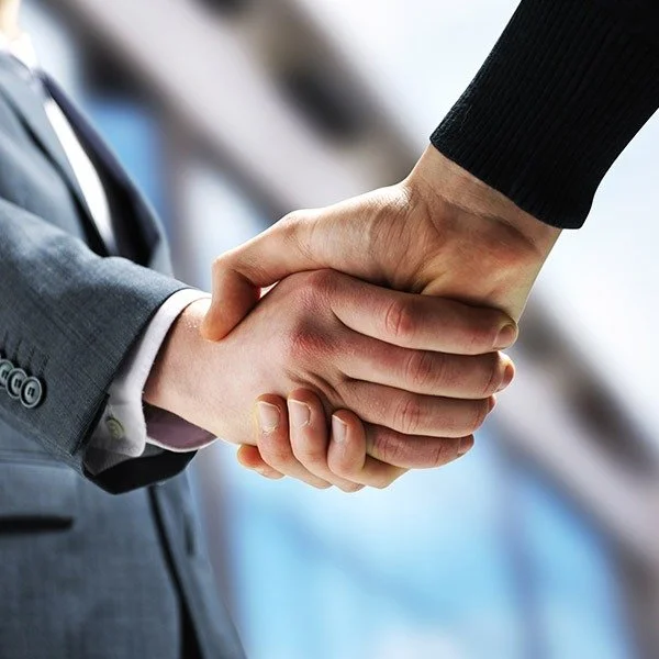 Close-up of two people shaking hands, one in a business suit, indicating a professional or business agreement.