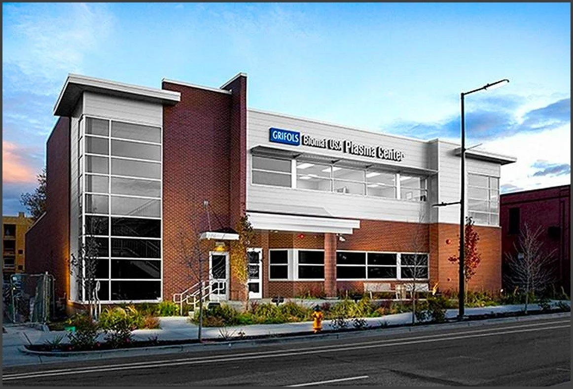 Exterior of a modern medical building with glass windows and brick facade, signage indicating it is a plastic center.