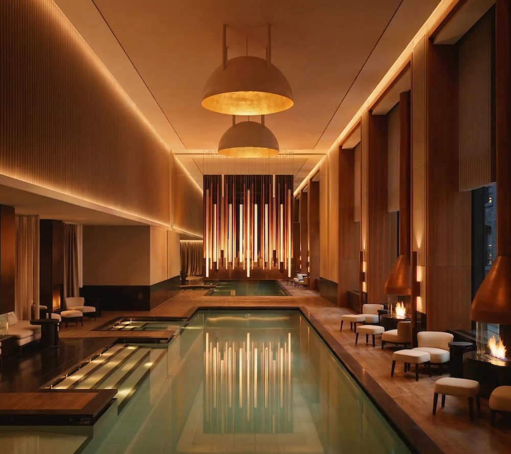 Elegant indoor pool area with warm lighting, modern pendant lights, and comfortable seating along the sides.