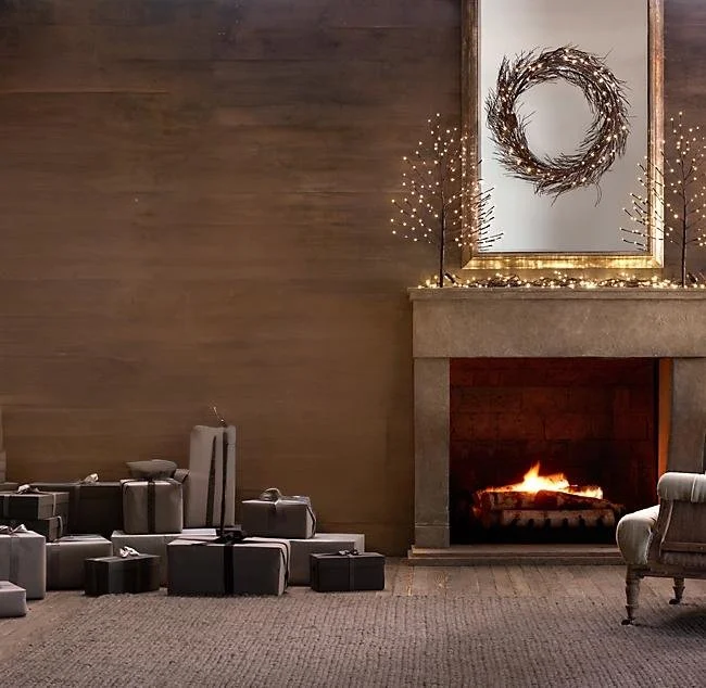 Living room with a decorated fireplace, holiday wreath, and several wrapped gifts on the floor.